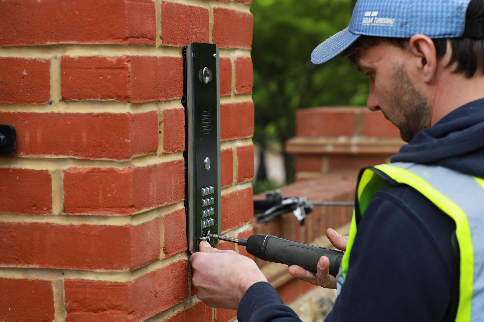 Engineer installing an intercom keypad on a brick gate post